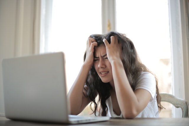A stressed woman at work holding her head in her hands
