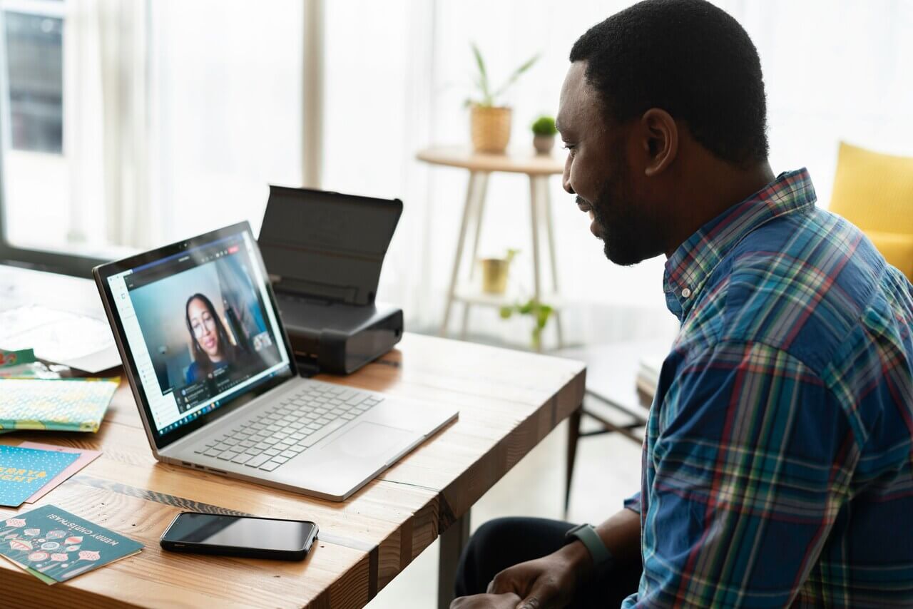 man speaking to woman in remote meeting on laptop