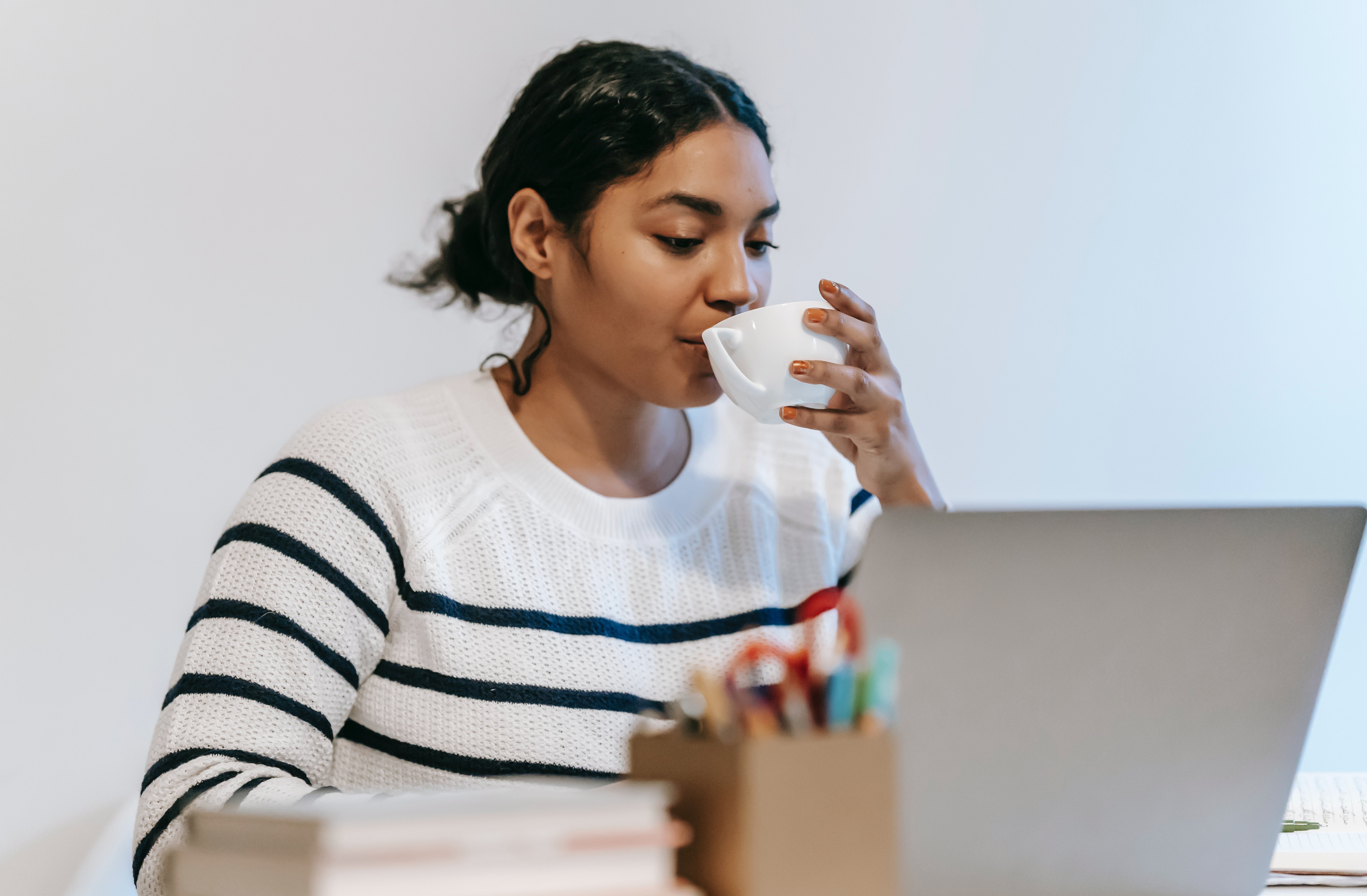 Young woman drinking coffee at her desk
